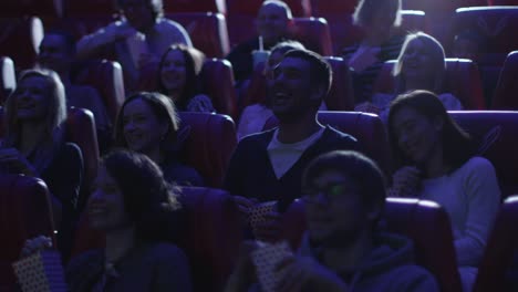 Grupo-de-personas-se-ríen-mientras-ven-una-proyección-de-la-película-de-comedia-en-un-cine-de-película.