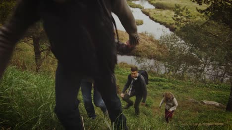 Grupo-de-hombres-y-mujeres-están-subiendo-por-una-colina-en-un-bosque-en-otoño-con-un-lago-en-el-fondo.