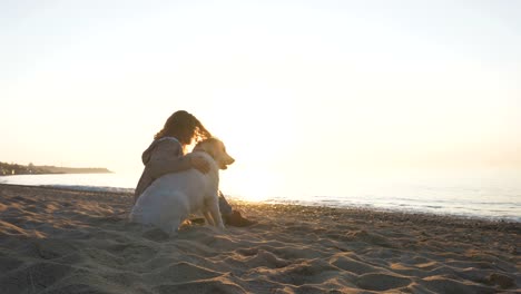 Junge-Frau-schnell-spielen-mit-Retriever-Hund-am-Strand-bei-Sonnenuntergang