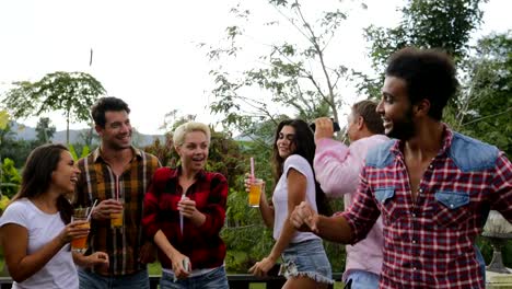 Junge-Leute-tanzen-kochen-Barbecue-Freundesgruppe-fröhliche-Zusammenkunft-Sommerterrasse-mit-Party