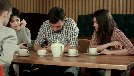 Group-of-young-people-sitting-at-a-cafe,-talking-and-drinking-tea