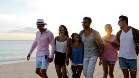 Gente-caminando-en-la-playa-hablando-en-puesta-del-sol,-los-hombres-alegres-y-grupo-de-mujeres-felices-sonriendo-comunicación-turistas-en-vacaciones-de-verano