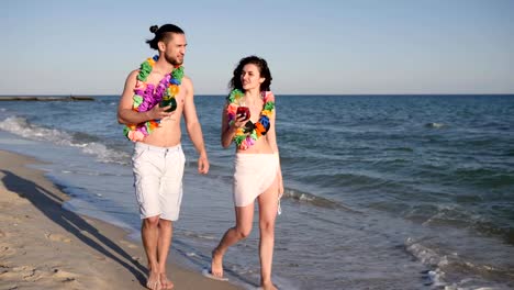 Caminar-descalzo-en-la-playa-de-arena,-par-en-bebida-de-amor-coloreada-cócteles,-viaje-romántico-de-Hawaii,-felicidad-gente-andando-en-el-resort