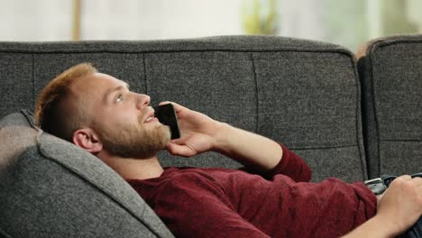 Handsome-young-man-relaxing-on-sofa-while-calling-his-girlfriend