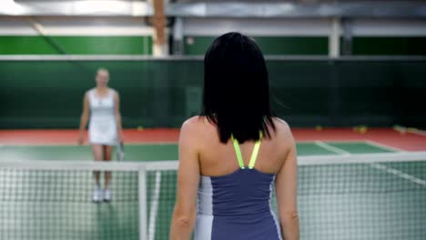 Zwei-schöne-Frauen,-die-einander-nach-dem-Spiel-zu-danken.-Professionellen-Tennisspielerinnen-der-Diskussion-über-das-Spiel-im-Erholungsgebiet.-Sportlerinnen,-die-Verlängerung-der-Anerkennung-für-ein-erfolgreiches-training