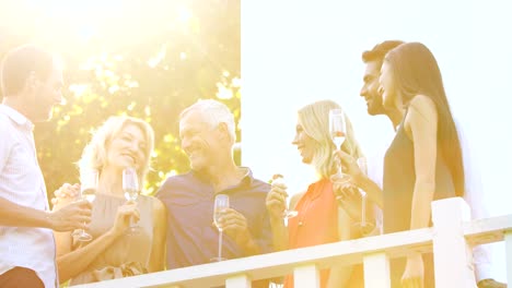 Freunde,-die-miteinander-interagieren,-während-mit-Champagner-in-Balkon