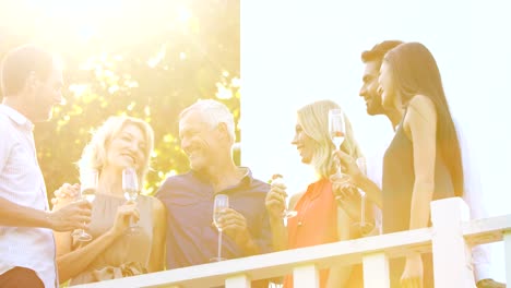 Friends-interacting-with-each-other-while-having-champagne-in-balcony