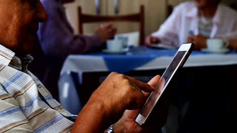 Senior-man-using-digital-tablet-with-his-friends-sitting-in-background-4k