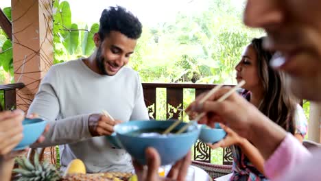 Menschen-ernähren-einander-mit-Delicious-Nudeln-asiatisch-Essen,-Freunde-Gruppe-sitzen-am-Tisch-auf-der-Terrasse-mit-Blick-auf-Wälder