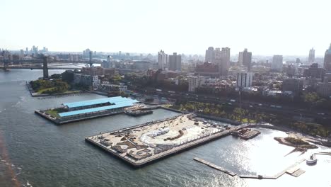 Aerial-view-of-the-Brooklyn-bridge-through-the-East-river-to-Brooklyn-district.-Drone-flying-over-the-pier-on-the-shore