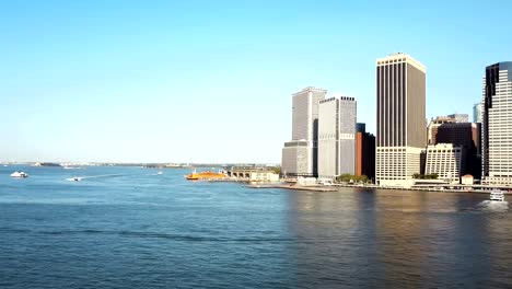 Aerial-view-of-the-Brooklyn-bridge-through-the-East-river-to-Manhattan.-Drone-turning-around-in-New-York,-America