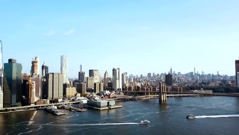 Aerial-view-of-the-Brooklyn-bridge-through-the-East-river-to-Manhattan-in-New-York,-America.-Boat-riding-on-the-shore