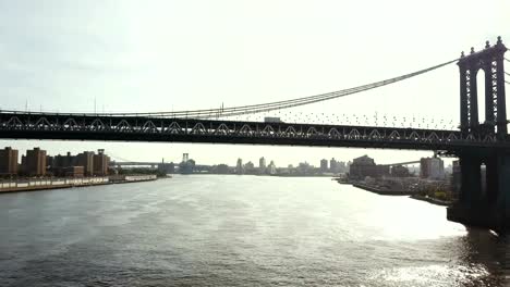 Aerial-view-of-Brooklyn-bridge-through-the-East-river-in-New-York,-America.-Drone-flying-under-the-road-on-the-bridge