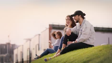 Atractivos-jóvenes-sentados-en-un-prado-verde-y-disfrutar-de-verano-en-la-ciudad