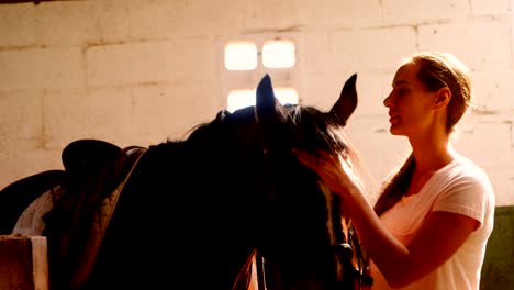 Woman-standing-with-the-horse-in-the-stable-4k