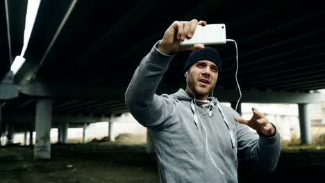 Athlet-Mann-mit-video-Chat-auf-Smartphone-mit-seinem-Trainer-nach-dem-Training-am-städtischen-Standort-im-Freien-im-winter