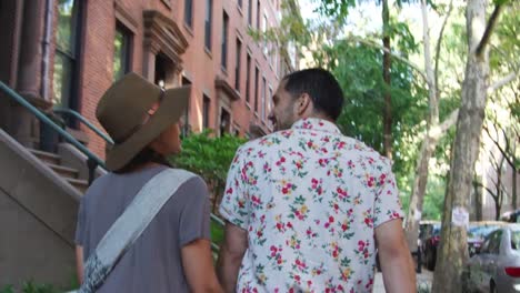 Rear-View-Of-Couple-Walking-Along-Urban-Street-In-New-York-City