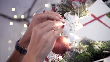 Schöne-Frau-steht-in-der-Nähe-der-Weihnachtsbaum-und-schmückt-sie-mit-Spielzeug