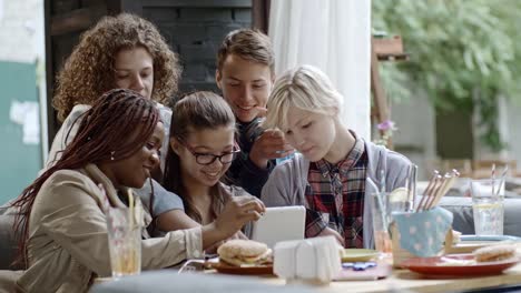 Compañía-de-adolescentes-con-tableta-Digital-en-el-café-al-aire-libre