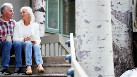 Senior-Caucasian-couple-sitting-on-wooden-cabin-steps