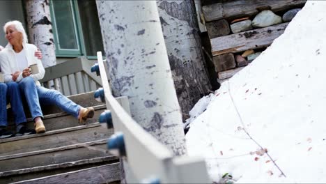 Senior-Caucasian-couple-sitting-on-wooden-cabin-steps