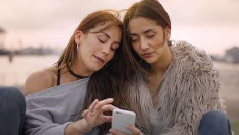 Dos-chicas-atractivas,-leyendo-un-artículo-sobre-un-teléfono-inteligente-en-un-día-soleado