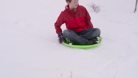 Boy-sledding-down-snow-covered-hill-in-winter