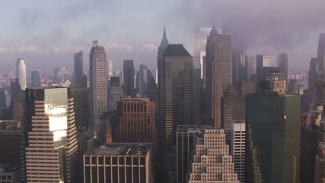 Verfolgung-durch-niedrigere-Manhattan-Gebäude-mit-niedrigen-Wolken-und-Sonne-am-frühen-Morgen.