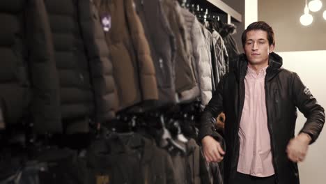 a-young-man-chooses-a-jacket-in-a-clothing-store,-he-tries-on-a-sample-for-himself