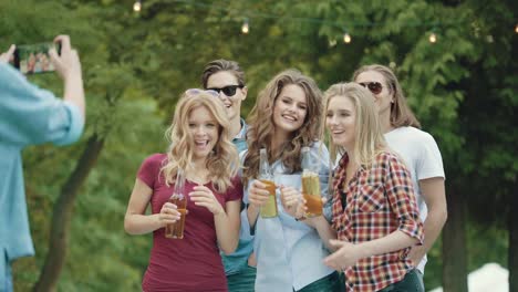 Happy-Friends-Taking-Photos-While-Dancing-And-Drinking-Outdoors.