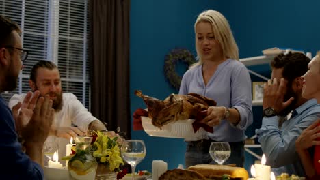 Woman-serving-holiday-turkey-on-dinner-with-friends