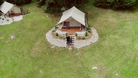 Aerial-view-of-couple-standing-in-front-of-sitting-area-at-a-camping-site.