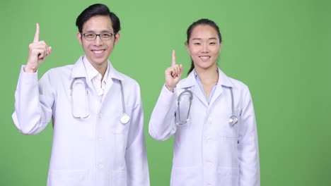 Médicos-de-la-joven-pareja-asiática-hacia-arriba-juntos