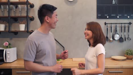 Beautiful-happy-asian-couple-are-dancing-in-the-kitchen-at-home.-Young-asian-couple-have-romantic-time-while-listening-music-at-home.