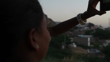 Two-women-silhouette-against-the-setting-sun-mobile-phone-photo-video-teamwork-romantic-viewpoint-love-bonding-together-tourist-rural-setting-friends-handheld-stabilized-lovers-follow--escape-surreal