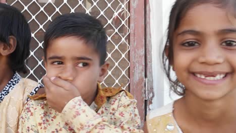 Pan-across-a-bunch-of-Indian-kids-smiling-and-laughing,-handheld-closeup