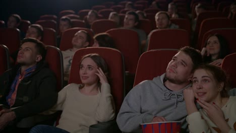 Amor-parejas-viendo-la-película-en-el-cine.-Joven-pareja-abrazándose-en-la-sala-de-cine