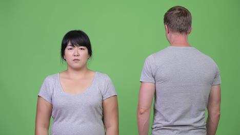 Young-multi-ethnic-couple-turning-and-crossing-arms-together