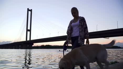 Beautiful-girl-walks-with-a-dog-along-the-river