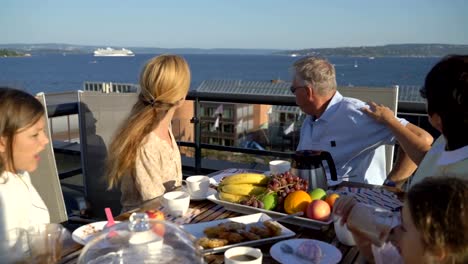 Eine-große,-glückliche-Familie-Abendessen-auf-der-Terrasse-hat-und-seine-Hände,-vorbei-an-der-Meer-Fähre-\"Wellenlinien\"