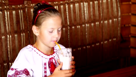 happy-smiling-teen-girl-child-drinks-a-milkshake-in-cafe.-she-is-dressed-in-Ukrainian-national-clothes,-embroidery,-vishivanka