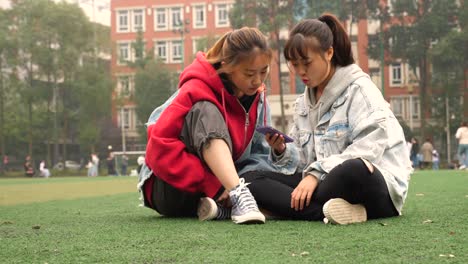 Zwei-glückliche-Asiatinnen-in-Campus-sprechen