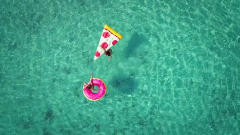 Luftaufnahme-von-zwei-jungen-Mädchen-schwimmen-und-spielen-im-Meer-mit-Hüpfburgen-zu-schließen.