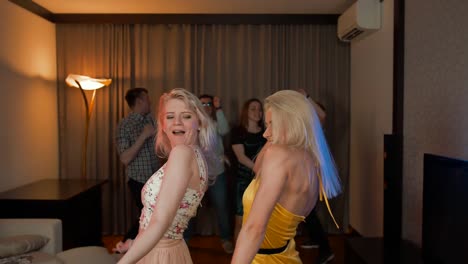 Two-attractive-sexy-girls-dancing-at-party-with-her-friends-behind