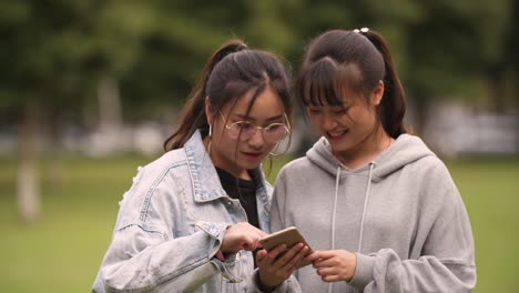 Two-asian-college-girl-using-mobile-phone-in-campus