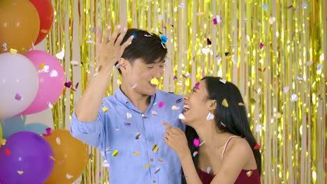 Young-asian-couple-enjoy-with-confetti-over-gold-glitter-background,-slow-motion.