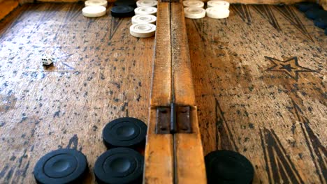 Two-young-men-playing-backgammon-on-a-wooden-table-rolling-dices-and-move-the-piece.