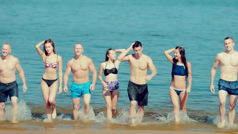 Group-of-friends-coming-out-of-the-water-on-the-beach.-Front-view