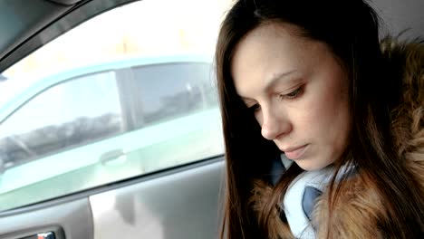 Woman-in-a-car-with-a-mobile-phone.-Young-beautiful-brunette-woman-looking-something-in-the-mobile-phone