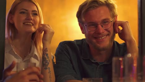 Two-guys-and-a-girl-laugh-talking-in-a-cafe-at-a-table